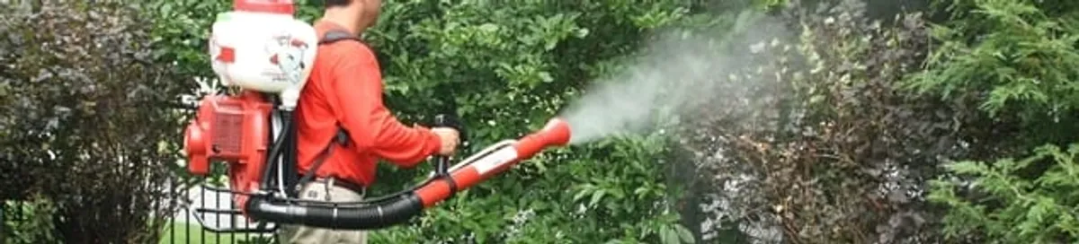 Mosquito control technician fogging shrubs and landscaping for mosquito treatment in Lowell, MA